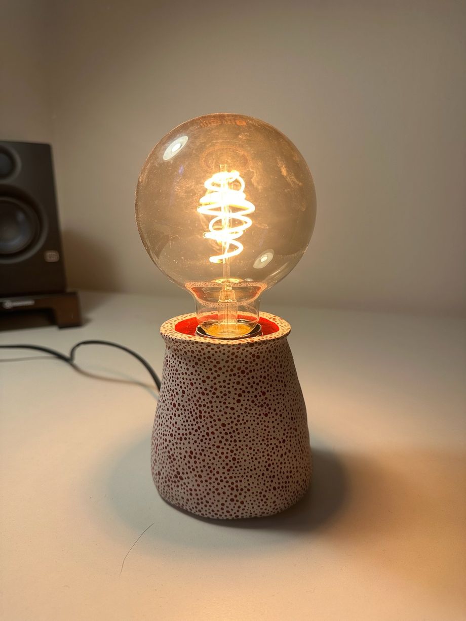 Lampa Kona Dots aprinsă pe un birou